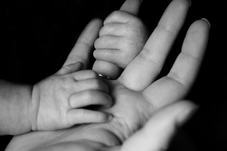 image of a mother and infant holding hands