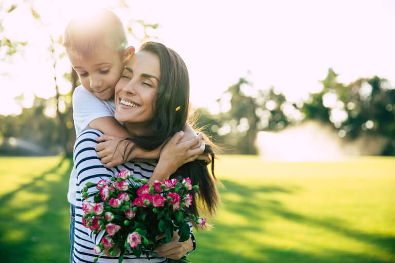 image of smiling young boy getting a piggy back ride from his smiling mom