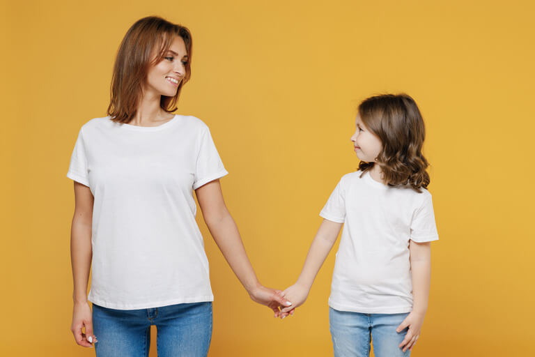 pic of a mom and young girl in t-shirts holding hands and smiling at one another