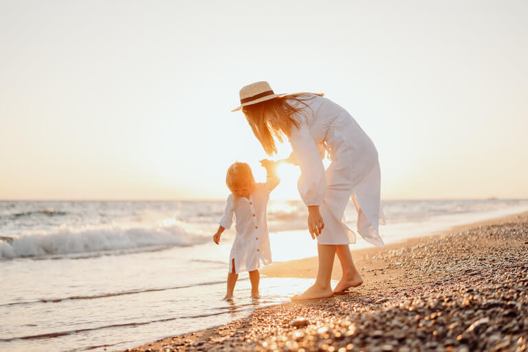pic of mother and small daughter walking hand in hand on a beach